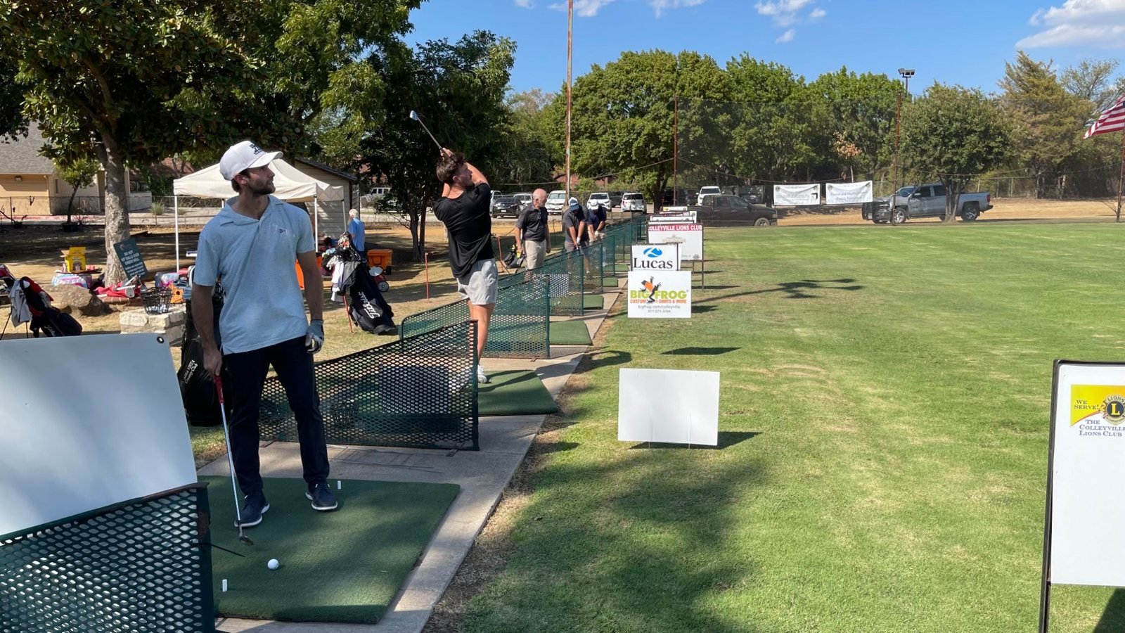 Golfers lined up along the driving range at the 2026 Hole-in-One Shootout, with sponsor signs on the turf